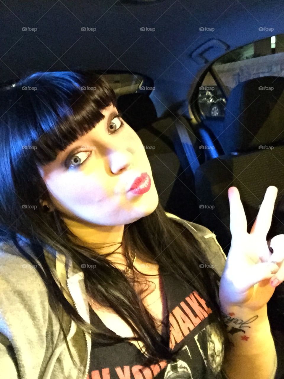 Beautiful girl showing victory sign inside car
