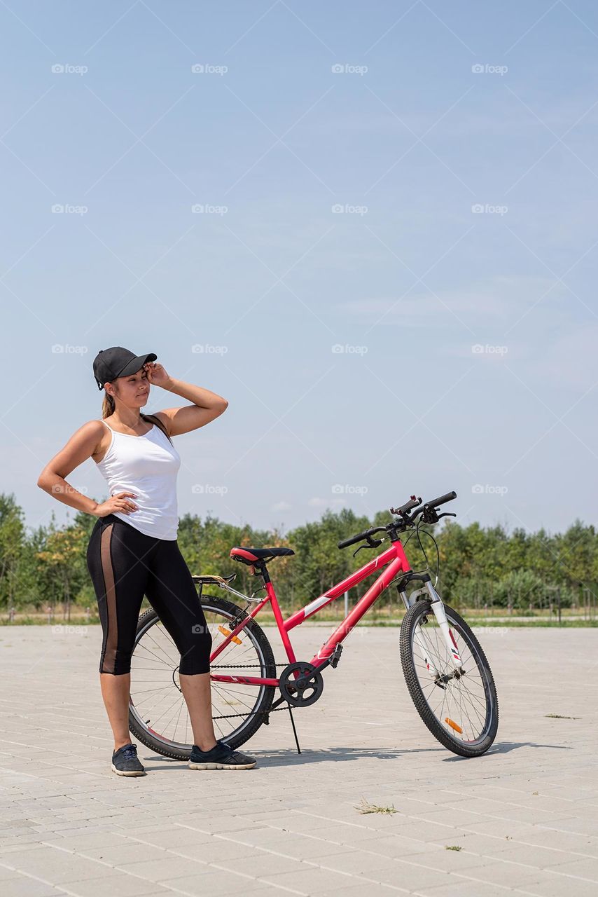 woman in sports clothes and cap riding her bicycle