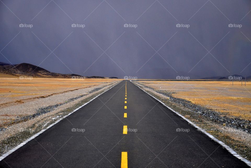 asphalt road in tibetan fields - road to stormy clouds