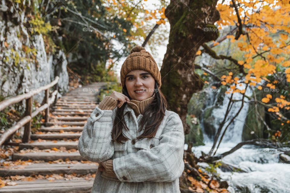 Portrait of young girl standing on wooden footpath in forest in autumn