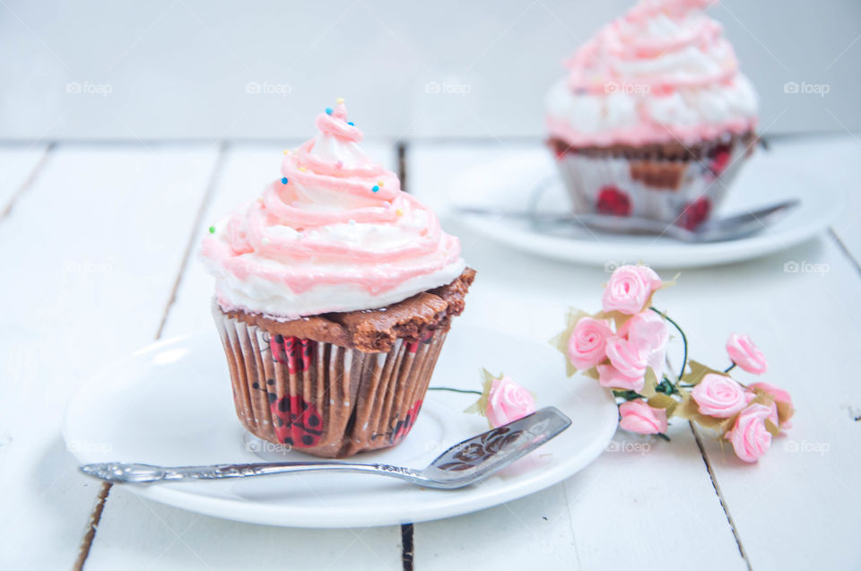 Delicious creamy cupcakes on wooden table