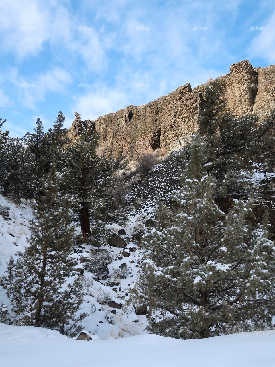 Cliffs of basalt stick out with just a bit of snow on the ground on a beautiful sunny winter day in Central Oregon. 