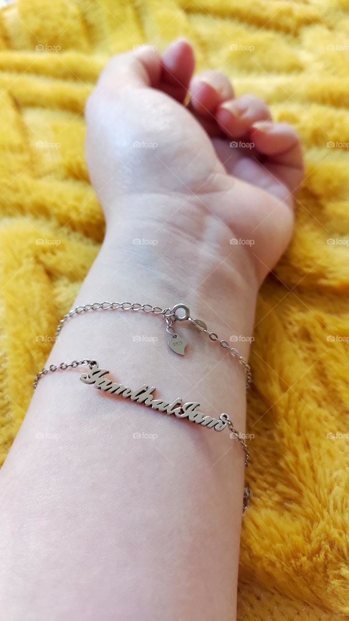Wearing customized silver bracelet on yellow fluffy background.
