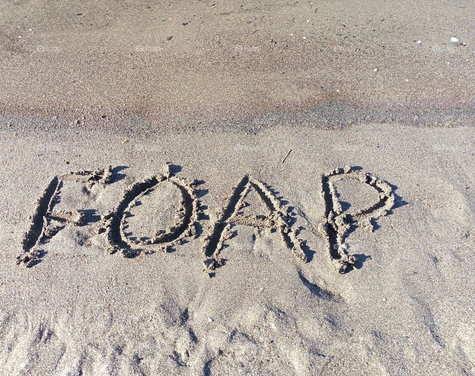 Foap letters written in the sand on a sandy beach