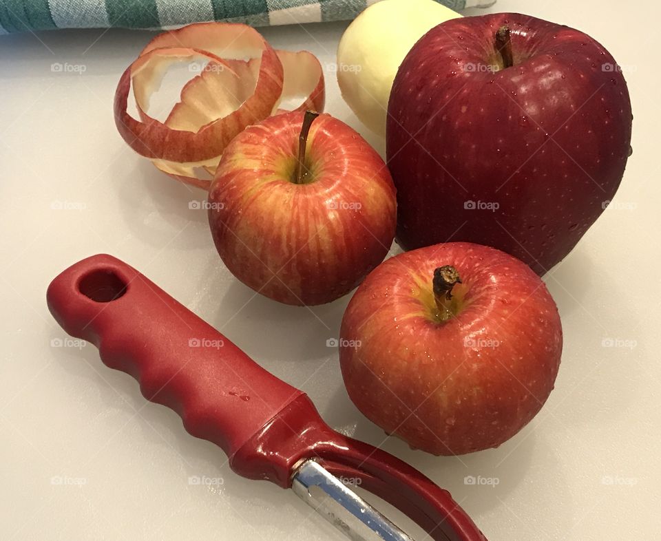 Red and peeled apples with peeler