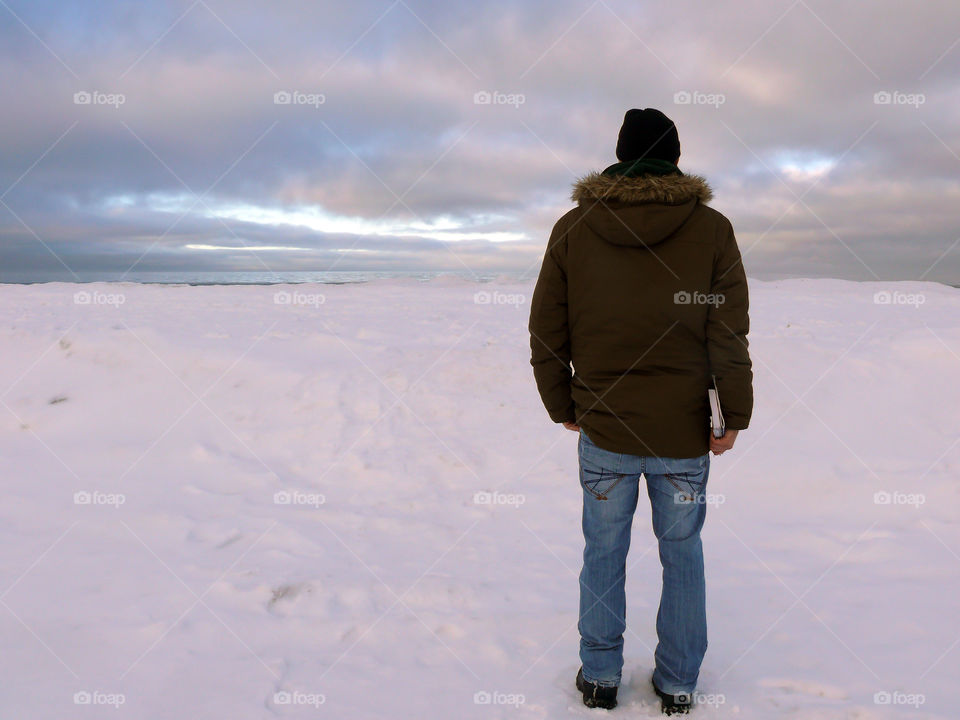 Rear view of young man standing on snow covered beach in Jūrmala, Latvia.