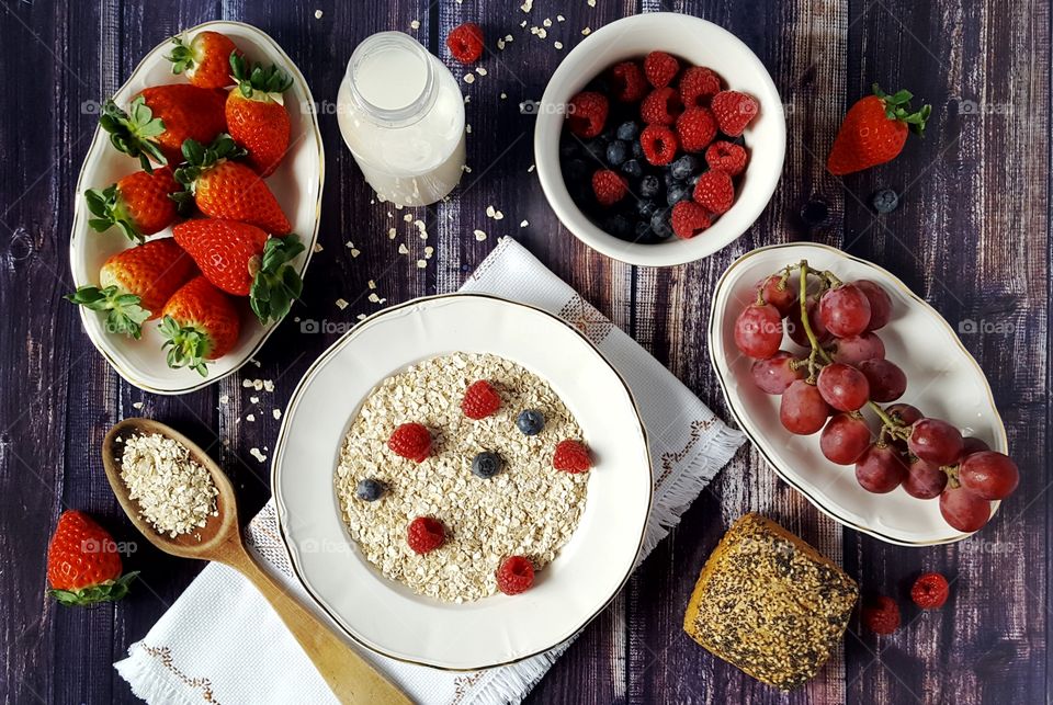 Healthy breakfast of oat flakes with milk, berries and fruit.