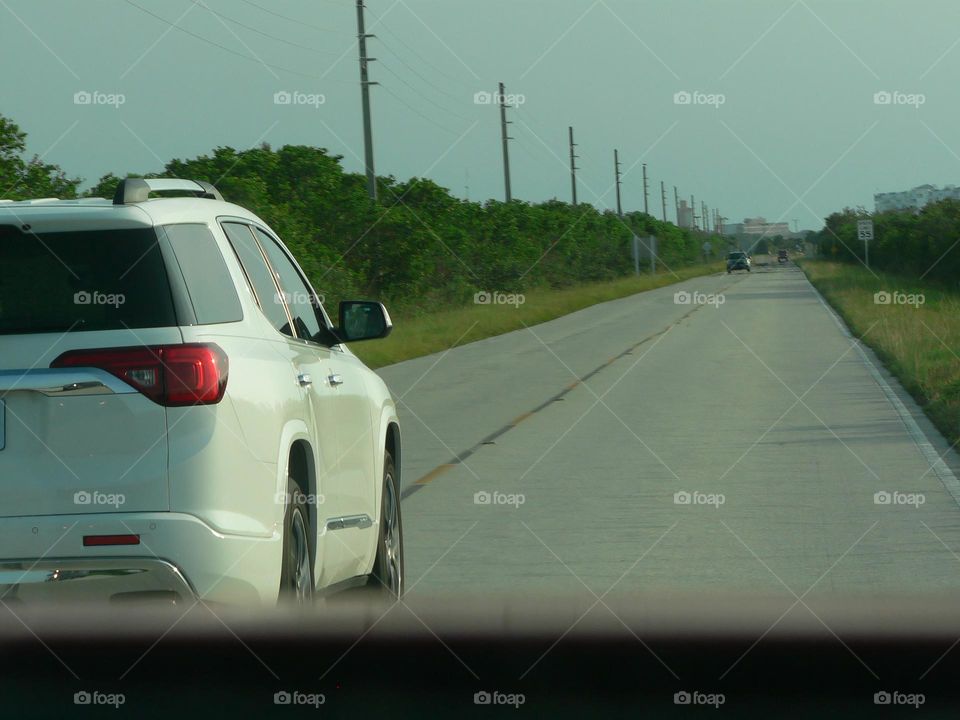 Road trip coming back from the beach in central eastern Florida by the Atlantic Ocean meeting some cars on the same side passing us and seeing vehicles on the opposite side of the road.