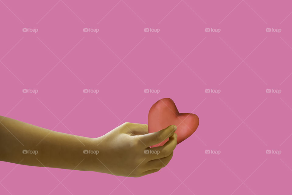 Hand holding a red candy shape heart on a pink background with clipping path for Valentine Day.