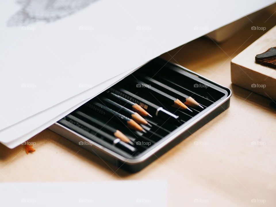 A set of pencils and white paper on a wooden table, nobody 