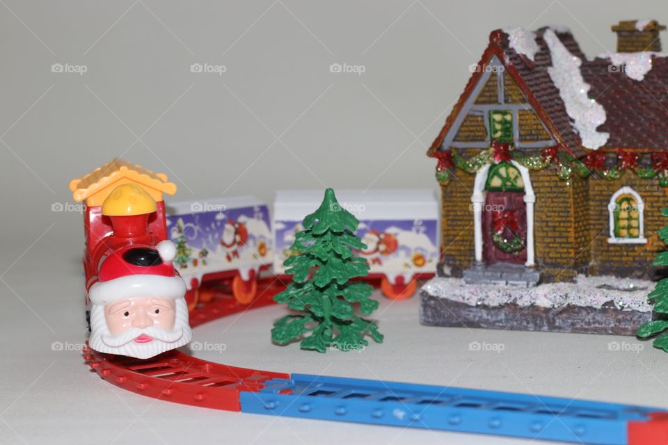 A funny toy train with face of Santa Claus, tree and a house with Christmas decorations 