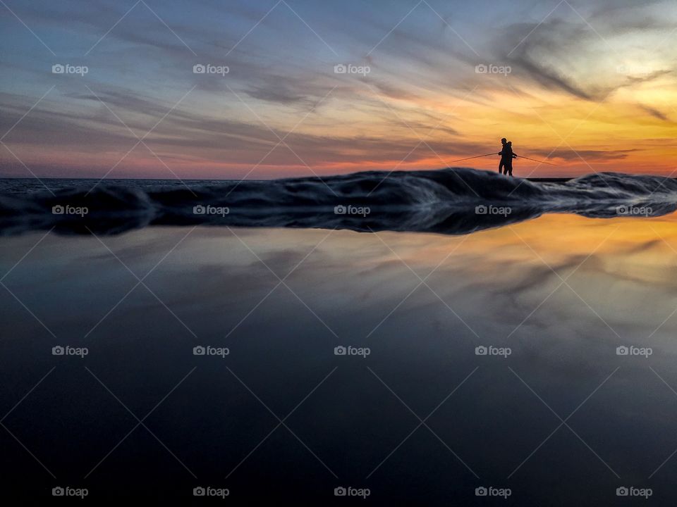 Silhouettes of fishermen fishing at sunset. 