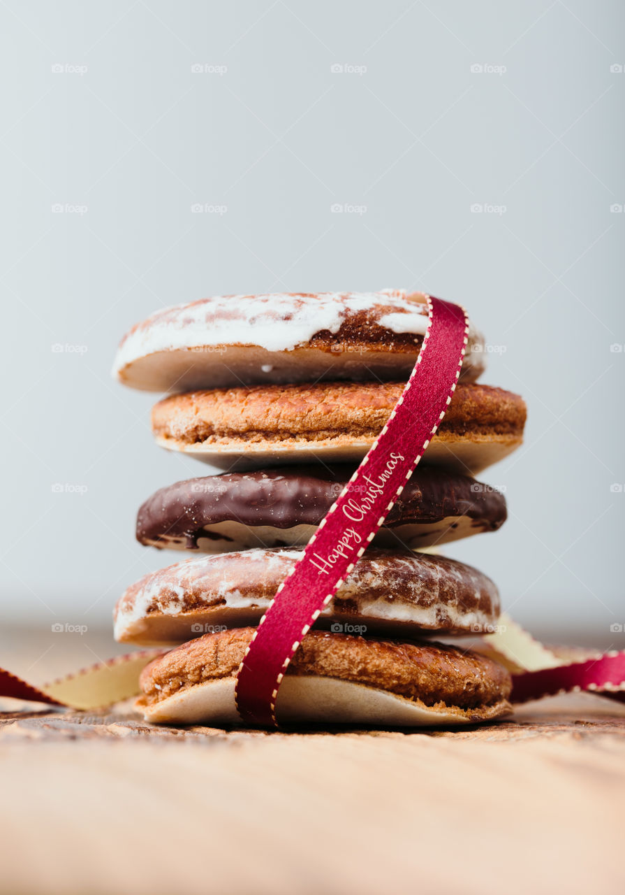 A few gingerbread cookies wrapped in red ribbon Happy Christmas on wooden table. Plain background. Portrait orientation