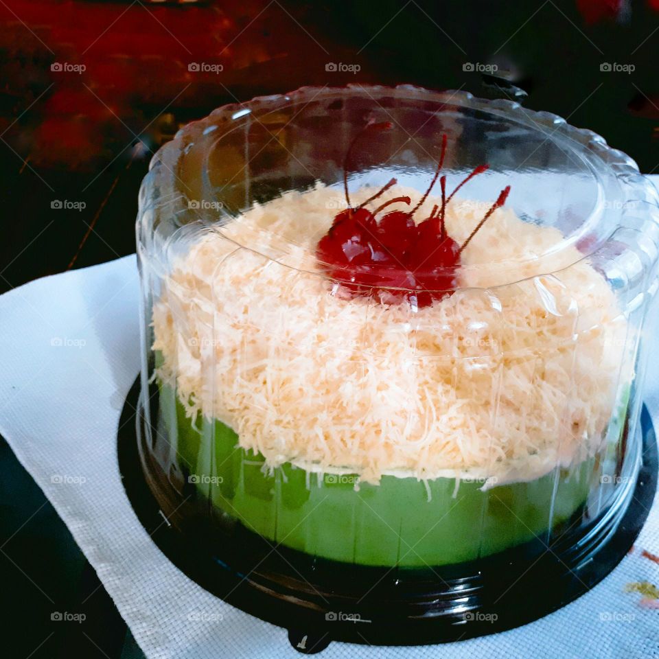 Green pandan cake sprinkled with cheese and cherries on top