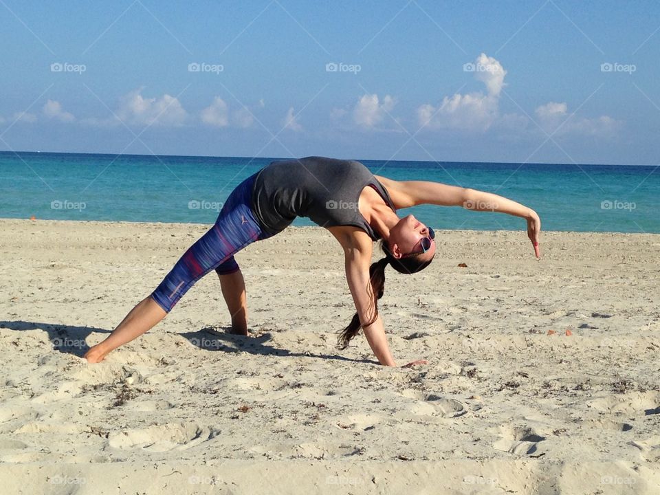 Fit Girl doing yoga on the beach in Cuba with Fitness clothing and sunglasses. 