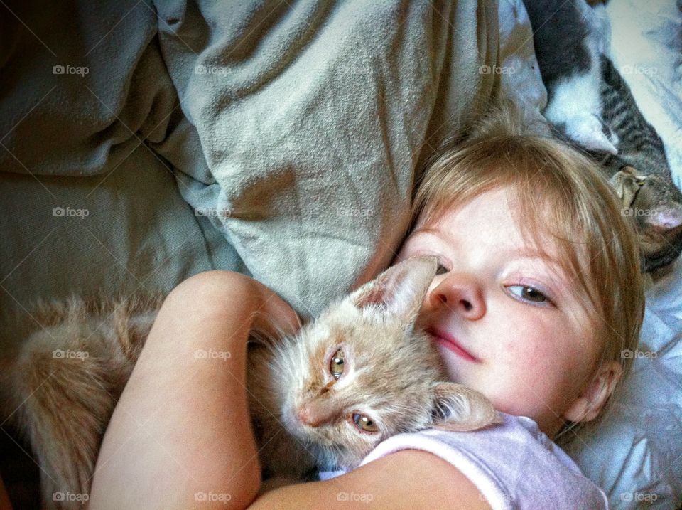 Little girl on bed with cute kitten