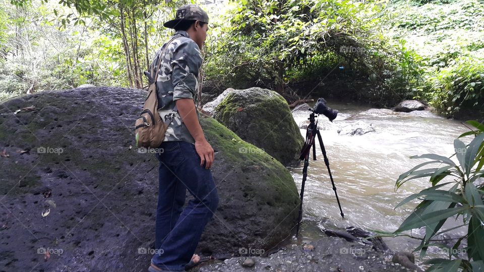 photographer in the jungle taking long exposure of the river