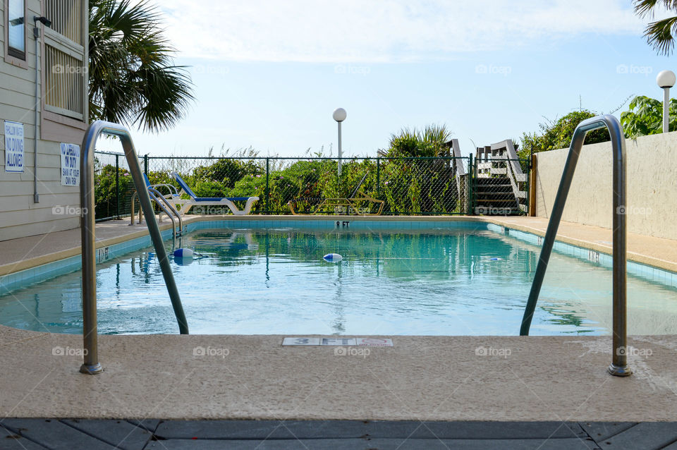 Eye level view of a dugout swimming pool outdoors with palm trees