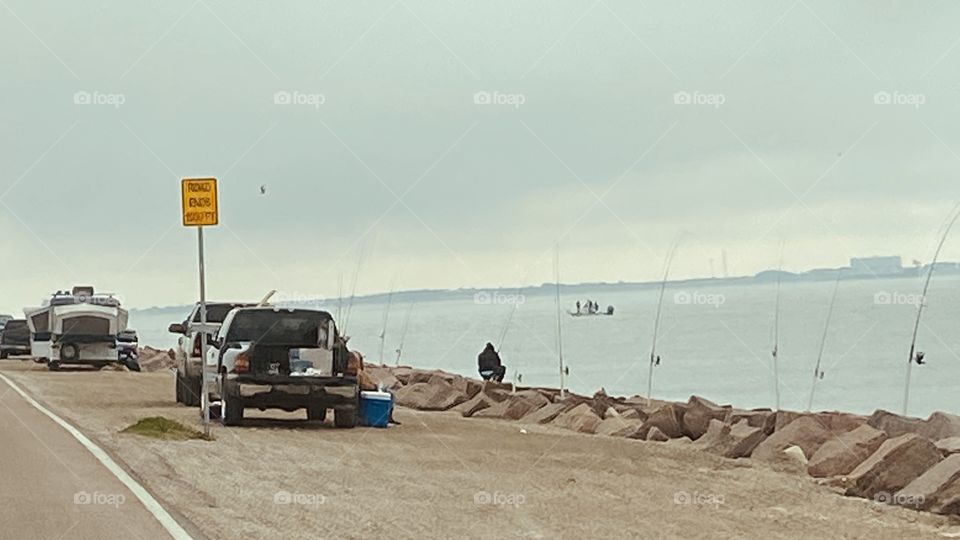Texas City Entrance to the 5 mile Texas City Fishing Dike. Fisherman along Dike with Fishing Poles set up on Granite Blocks Waiting on Fish Hitting Baits.