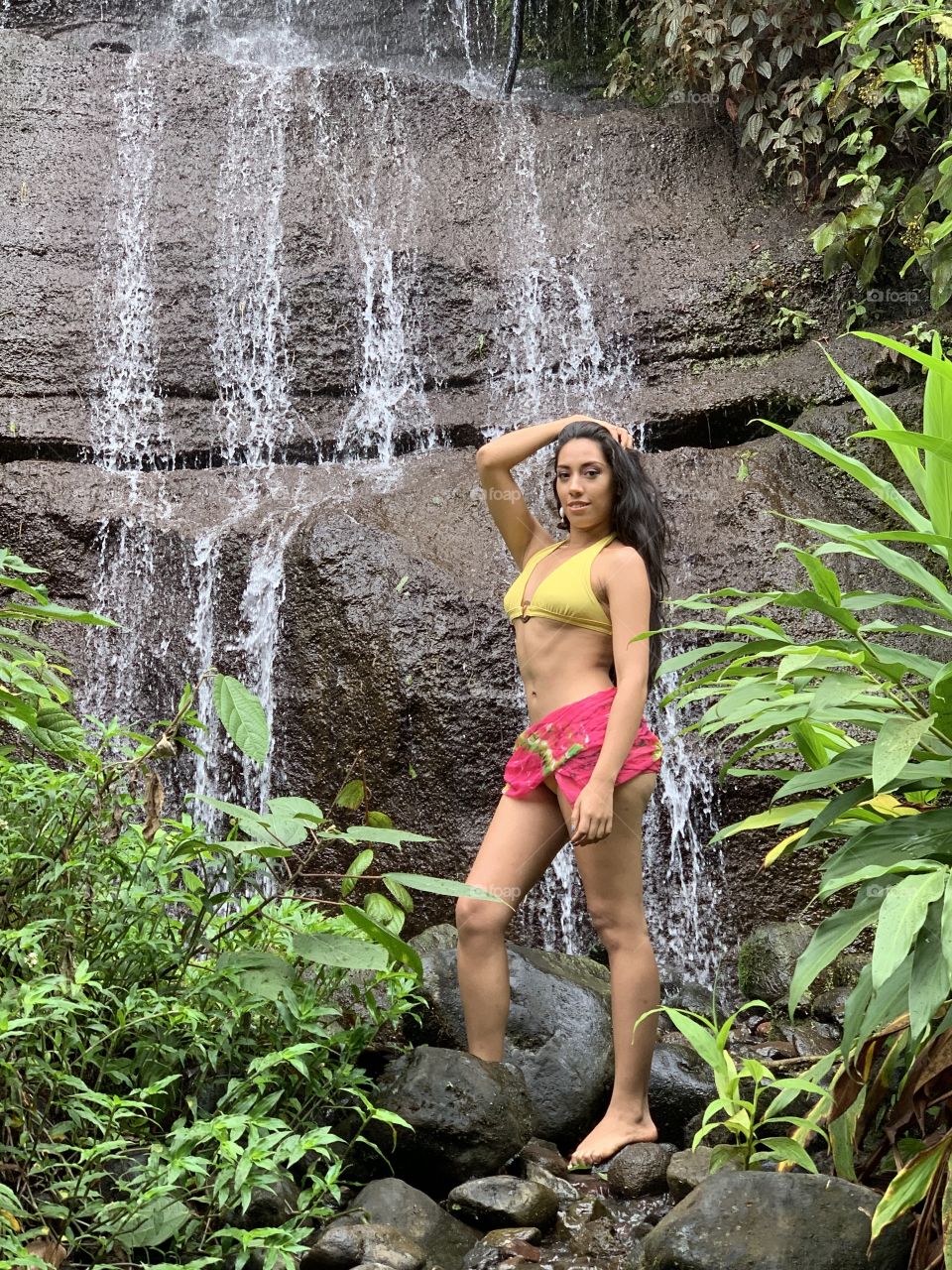Girl in waterfall in swimming suit 
