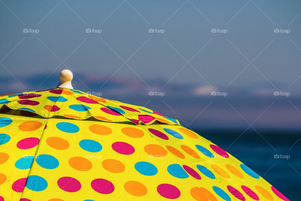 Yellow polka dot umbrella by the ocean on the beach in Capitola California, multi colored 