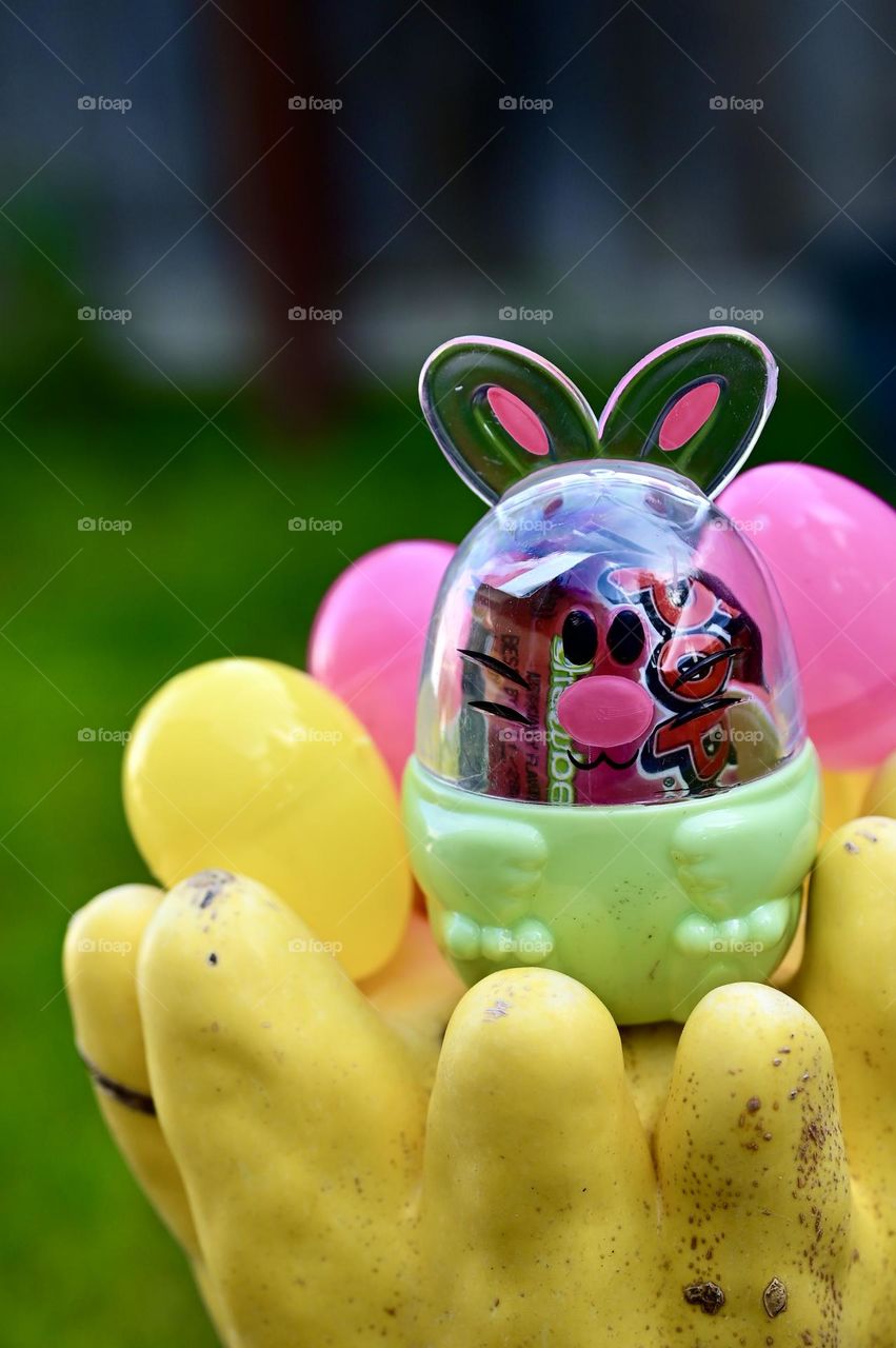 Portrait close up shot of egg bunny on the unique yellow pumpkin with blurry green background.