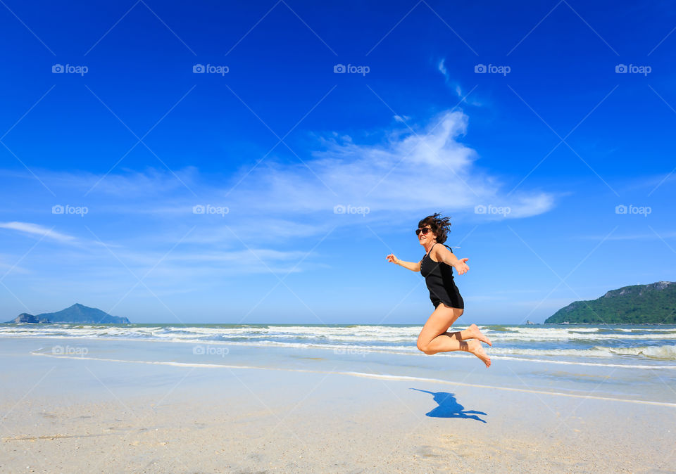 Scenic view of happy woman jumping on beach