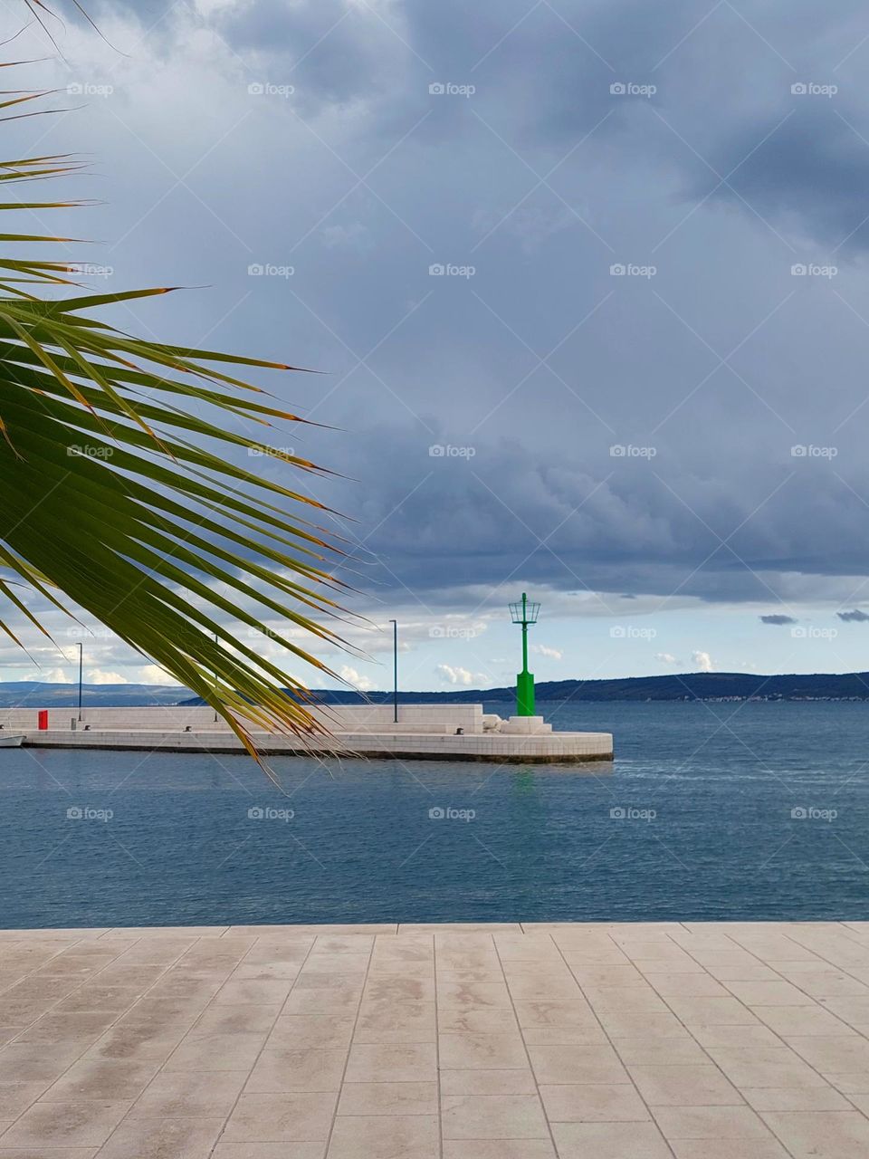 Seascape.  An empty shore and calm sea as the clouds gather before the storm