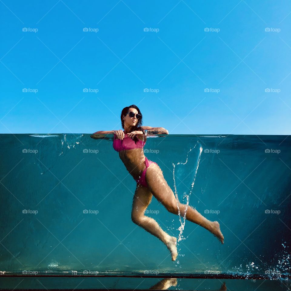 Swimming pool girl in pink bikini blue water