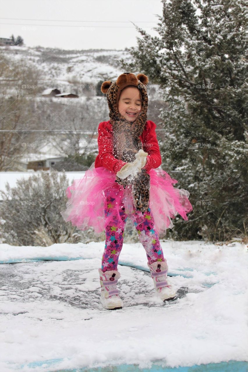 Smiling girl dusting snow in winter