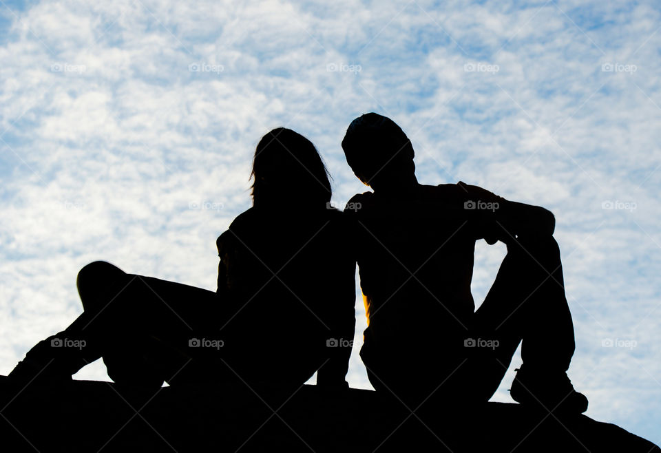 Two silhouettes of a girl and a guy on a sky background
