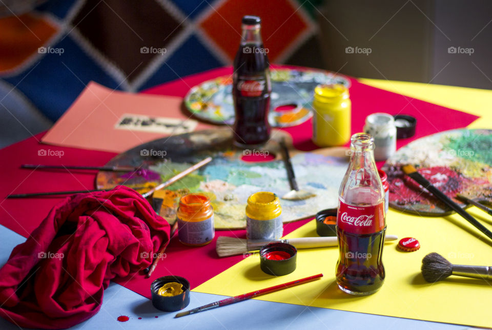 Coca-Cola bottles and colorful painting materials on the table