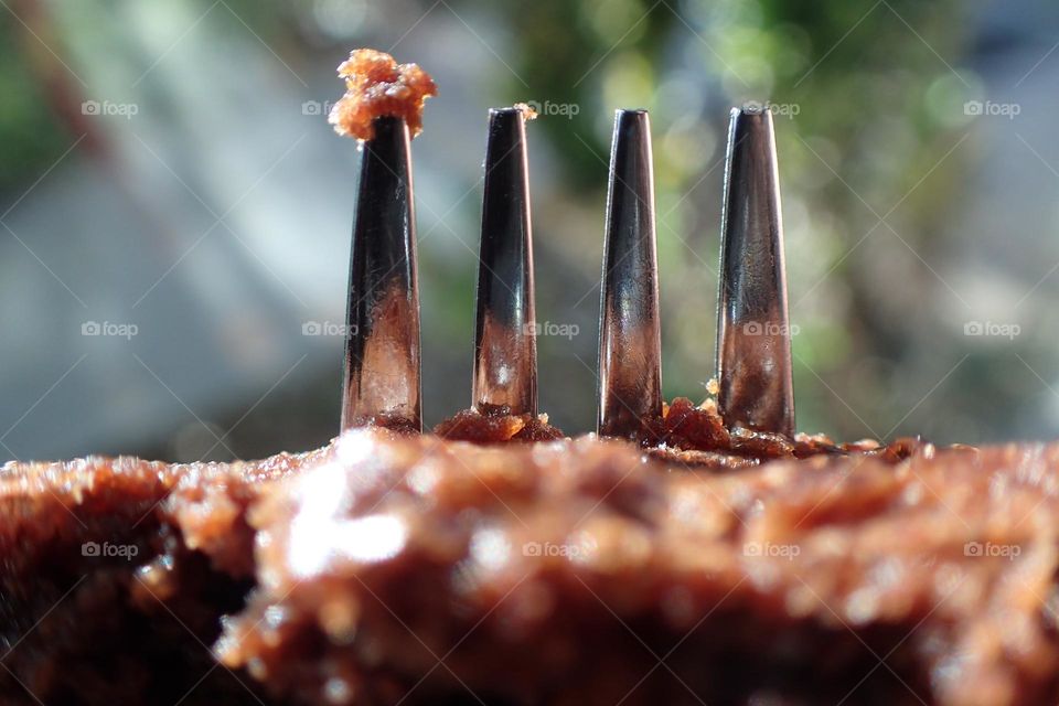 Fork prongs piercing through a brownie crumb on top of prong