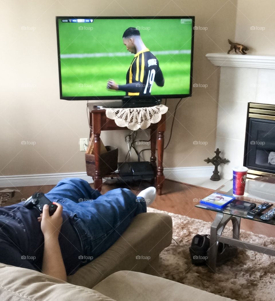 Teen male playing sports video game in living room 