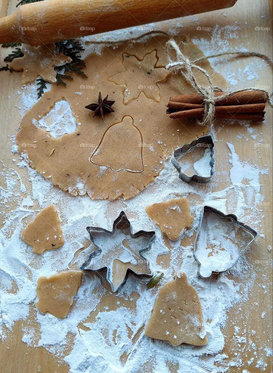 Preparing for Christmas and New Year. Composition: rolled ginger dough, wooden rolling pin, dough forms, metal dough molds, cinnamon sticks tied with a rope, anise. All items are on the board with flour