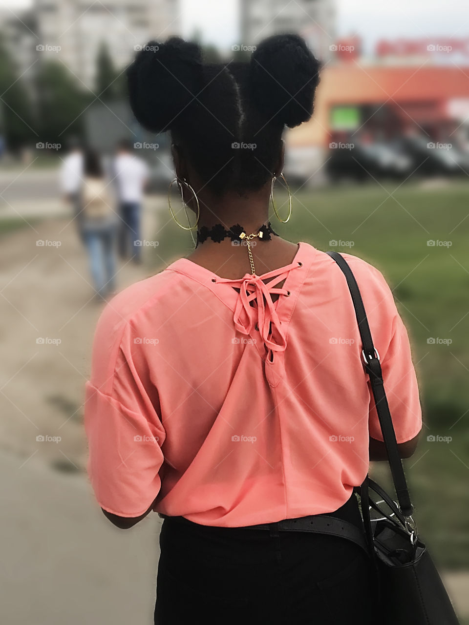 Young African woman with stylish haircut walking in the city 