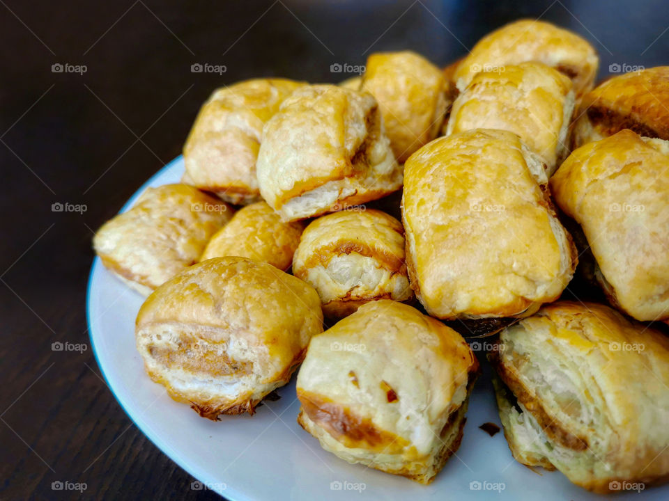 Sausage rolls in a white plate on wood table.