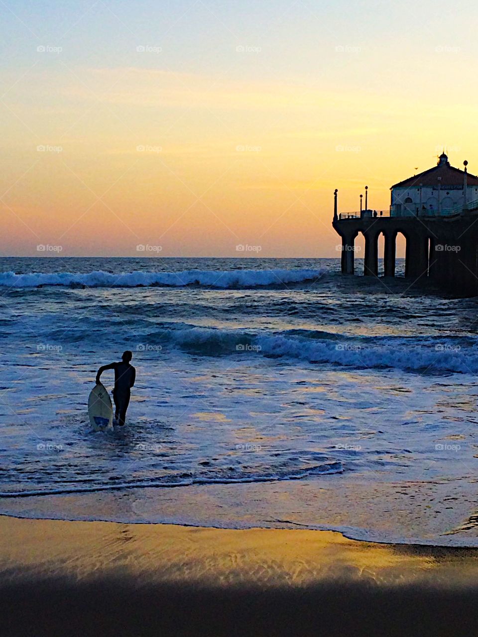 Surfer pauses before heading in at Manhattan Beach, CA.