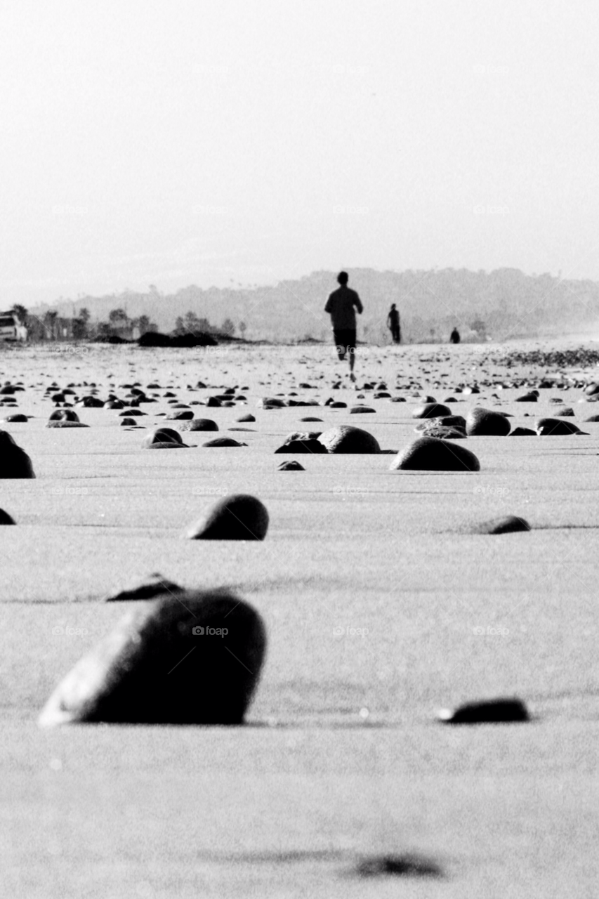 beach rocks black and white running by PhotoSpect
