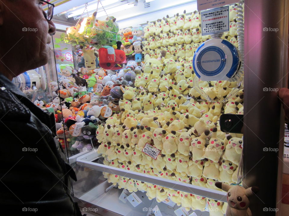 Man Playing UFOCatcher / Crane Machine Game. Pikachu Plushies, Pokémon. Tokyo, Japan