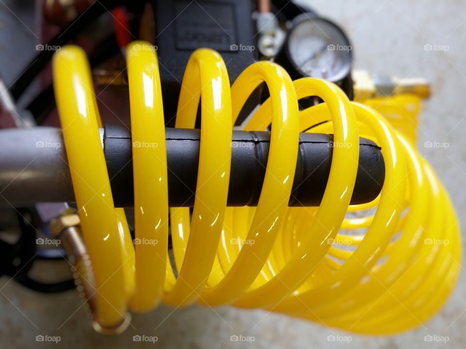 The bright yellow of an air compressor hose coil