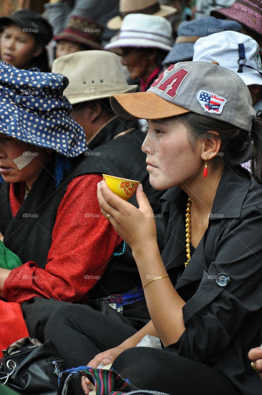 woman drinking tea during buddha festival in the yard of buddhist monastery in shigatse