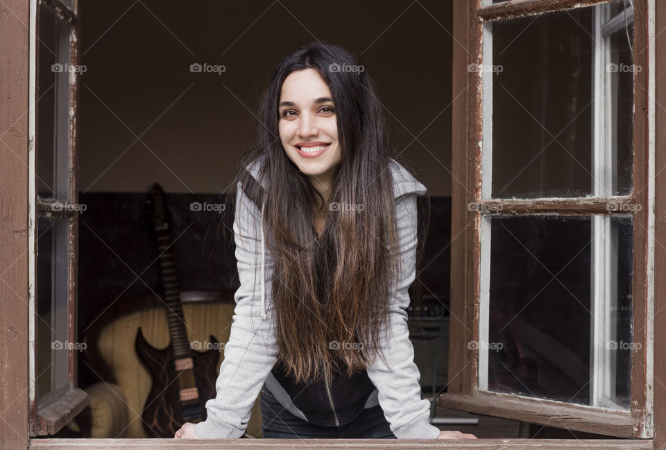 Portrait of beautiful woman with long hair on the window