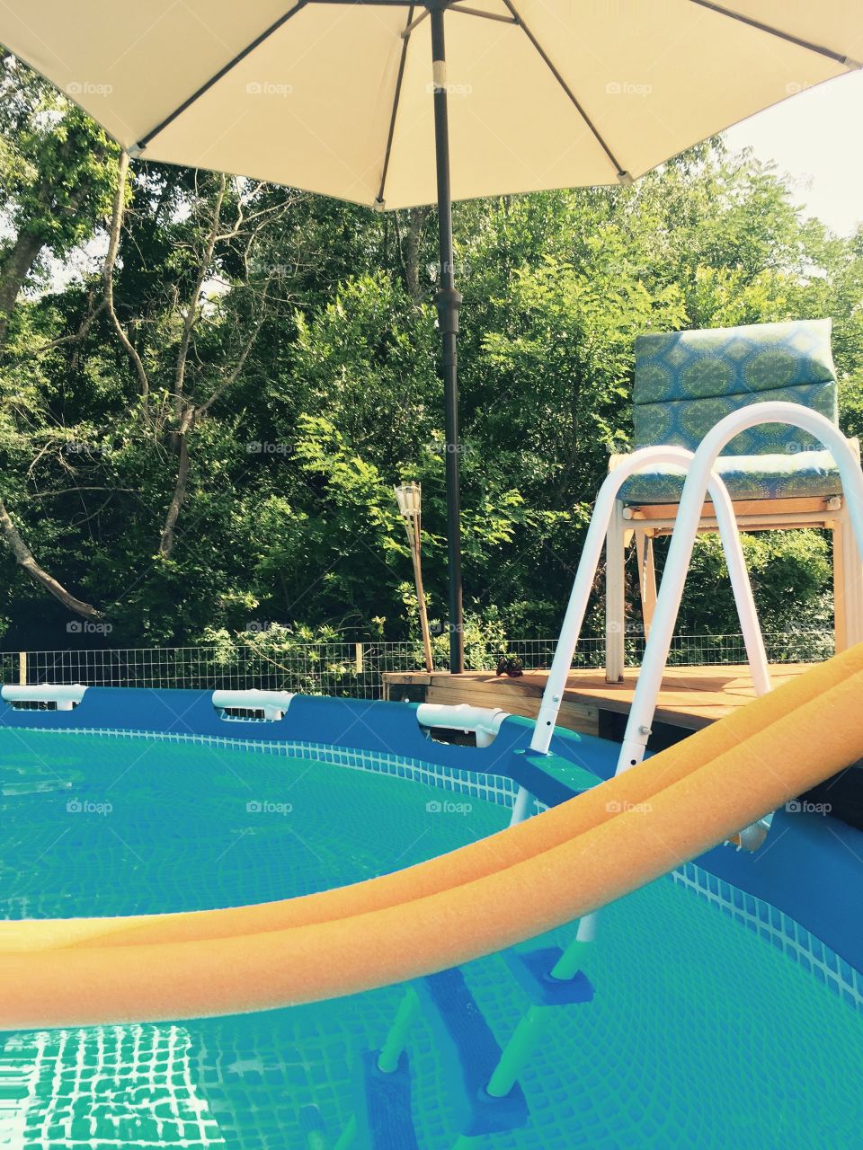Orange floater noodle  in the pool by the ladder. 