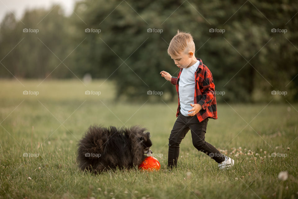 Little boy playing with his dog in soccer in a park 