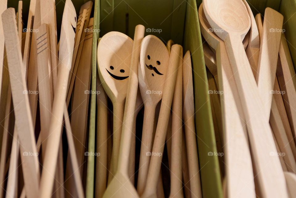 Handmade wooden spoons with funny smiles. Wood products on the counter.
