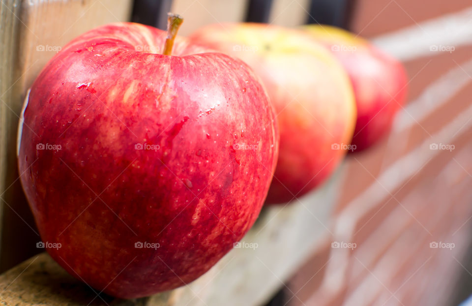 Row of beautiful fresh red apples on wood fence next to brick wall closeup nutritional healthy eating choices and wellness food photography 
