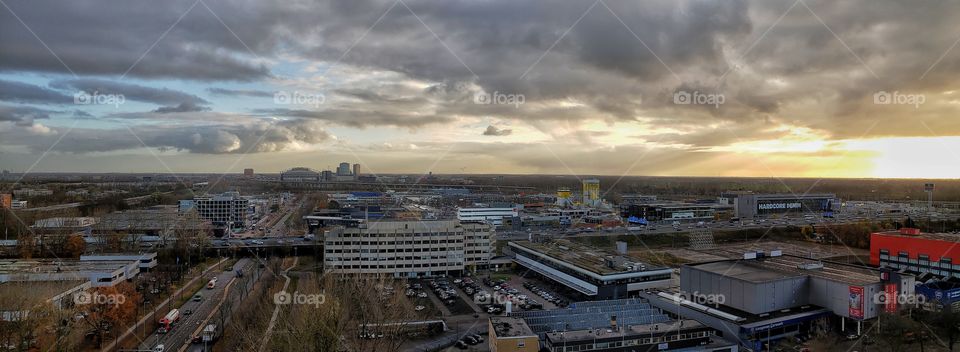 Panorama elevated view of the cityscape at Amsterdam, The Netherlands. Dramatic cloudscape in the setting sun.