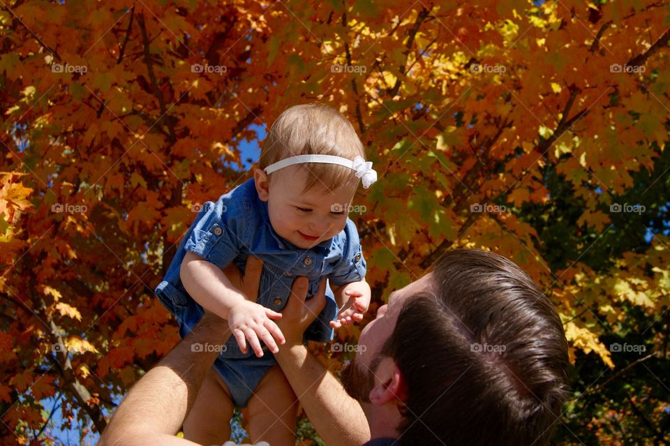 Father with his daughter near tree during autumn