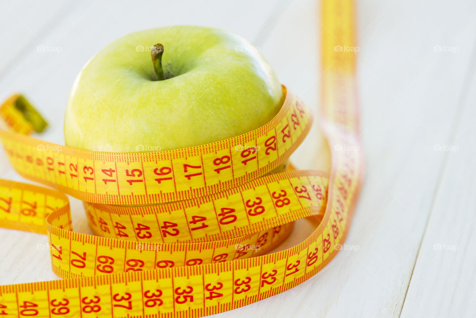 Dieting concept. Green apple with measuring tape. Green apples measured the meter, sports apple